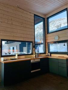 een keuken met drie ramen in een houten muur bij Luxury Arctic Cabin in Øverbygd