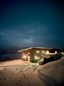 een huis in de sneeuw 's nachts met lichten bij Luxury Arctic Cabin in Øverbygd