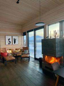 een woonkamer met een open haard en een bank en stoelen bij Luxury Arctic Cabin in Øverbygd