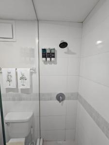 a white bathroom with a shower with a toilet at Portmore Paradise in Portmore