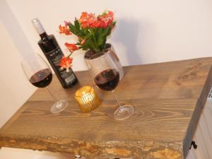 Ferienwohnung Apartment Fewo Alojamiento Casa Demy في بابينهاوزن: كأسين من النبيذ و إناء من الزهور على طاولة