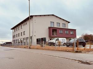 a building with two cars parked in front of it at PEN Smart Hotel in Türkheim