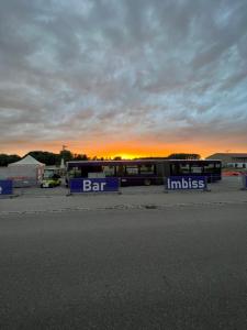 two buses parked in a parking lot with the sunset in the background at PEN Smart Hotel in Türkheim