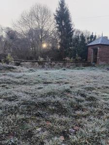un campo coperto di brina con una casa sullo sfondo di Studio chez Claudine a Conches-en-Ouche