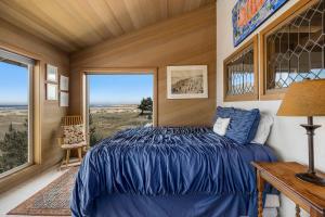 ein Schlafzimmer mit einem blauen Bett und einem großen Fenster in der Unterkunft Fantastic Beach View! Oregon Escape with Game Room in Seaside