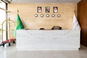 a white counter in a room with a wall with clocks at فندق رويال اديشن للشقق الفندقية in Buraydah