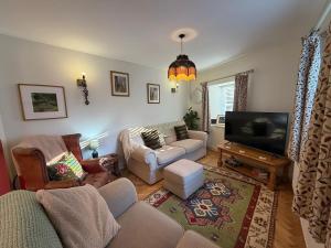 a living room with a couch and a tv at Half Pint Cottage in Uplyme