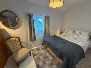 een slaapkamer met een bed, een stoel en een spiegel bij Half Pint Cottage in Uplyme