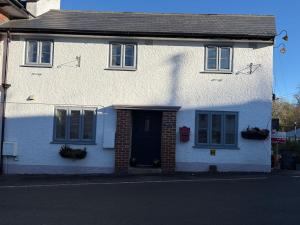 een wit huis met een zwarte deur en ramen bij Half Pint Cottage in Uplyme