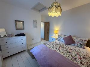 a bedroom with a bed with a dresser and a lamp at Half Pint Cottage in Uplyme