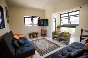 a living room with a couch and chairs and a tv at Casa com Vista para a Praia e Área Gourmet in São Sebastião