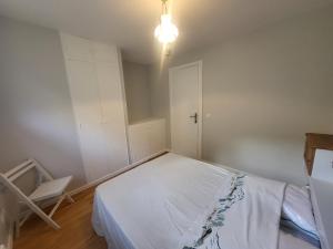 una camera da letto con un letto bianco e una sedia di Chalet Claree a Val des Pres a Le Rosier