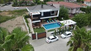 two cars parked in front of a house with a swimming pool at Villa SONNE in Antalya