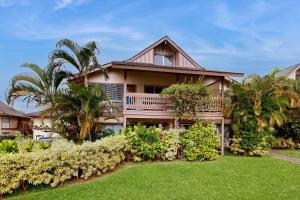 a house with a balcony and lush green yard at SandPiper #116a in Princeville