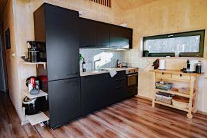 a kitchen with black cabinets in a tiny house at Unique Hideaway by Krøderen - Beach, Boat & Hiking in Ørgenvika