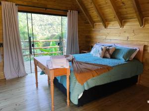 a bedroom with a bed and a desk with a window at cabana Eco da Natureza in Praia Grande