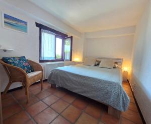a bedroom with a bed and a chair and a window at Casa Leyian - Free parking in Brissago