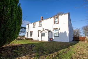 Spa & Rose Cottages Gilsland في Gilsland: بيت ابيض قديم وامامه شجره