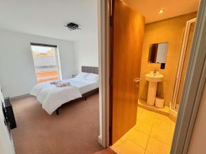 a bedroom with a bed and a bathroom with a window at Modern 2 Bed Apartment in York City Centre - Best York Location - Steps from Top Attractions in York +14 photos
