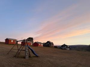 a playground with a slide in a field with houses at Skåbu Camping in Skåbu