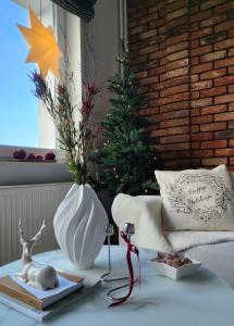 华沙7th Floor Apartment Mokotów的客厅里摆放着一棵圣诞树和一个白色花瓶。