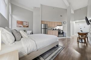 a white bedroom with a large bed and a kitchen at Relaxing studio perfect for extended visits in New Haven