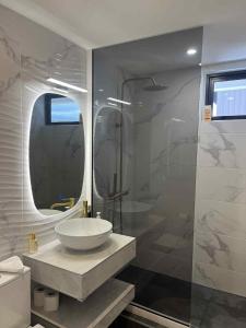 ein Badezimmer mit Waschbecken und Glasdusche in der Unterkunft Ali'i Tahiti in Papeete