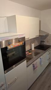 Work and Stay Plettenberg 90 Qm 7 Betten 3 Schlafzimmer mit Balkon und Kraftraum 44 oben في بليتنبرغ: مطبخ فيه دواليب بيضاء وفرن اسود