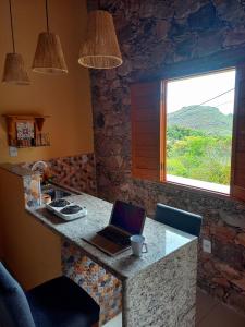 a kitchen with a laptop on a counter with a window at Loft de Cristal Igatu in Andaraí