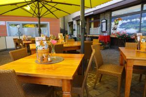 Familie Lampersberger في Sachsenburg: مطعم بطاولات وكراسي خشبية ومظلات صفراء