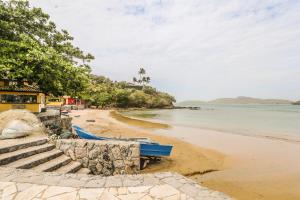 a beach with a blue boat on the sand at Casa Maju Suites in Búzios