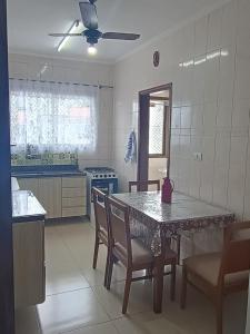 a kitchen with a table with chairs and a ceiling fan at Apto 2 quartos com Piscina e Vista Mar Oportunidade Única in Mongaguá