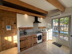 La Petite Maison Dans Les Vignes في Chamaret: مطبخ بدولاب خشبي وموقد