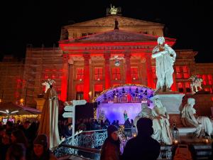 un grupo de personas de pie en frente de un edificio con una estatua en Downtown Landmark near Checkpoint Charlie - fully preserved, en Berlín