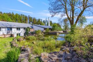 een huis met een vijver ervoor bij Resort Papírna50 in Lauterwasser