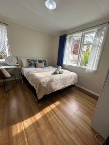 Un dormitorio con una cama y dos ventanas. en Northcote Holiday Home Rooms, en Auckland