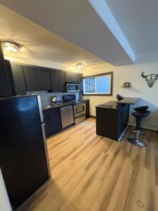 a kitchen with black cabinets and a wooden floor at Cozy boho downtown apartment in Calgary +13 photos