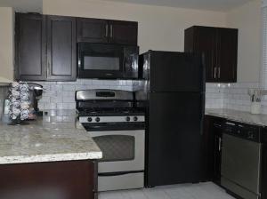 a kitchen with a black refrigerator and a stove at The Cozy Luxe Retreat, Central West End in Saint Louis +6 photos