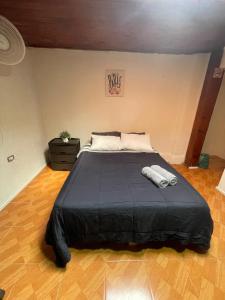 a bedroom with a large bed with a black comforter at Habitación doble en el centro con baño privado in Curicó