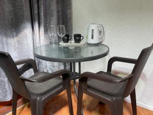 a glass table with two chairs and a coffee maker on it at Habitación doble en el centro con baño privado in Curicó