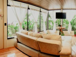 a living room with a couch and large windows at Cabañas Caeli, El Colibri, NEW La Fortuna Rainforest Cabin w Panoramic Views in San Francisco