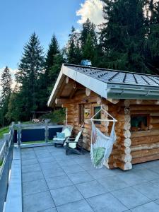 a log cabin with a hammock on a patio at The Forest House in La Comballaz