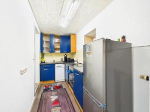 Apartment in Kordel في Kordel: مطبخ مع دواليب زرقاء وثلاجة