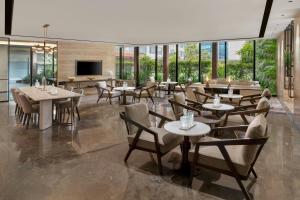 Un comedor con mesas y sillas y ventanas. en Courtyard by Marriott Mumbai International Airport, en Bombay