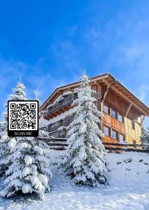 Un pino cubierto de nieve frente a un edificio. en Luxury Chalet Liosa - Ski in Ski out - Amazing view, en Corvara in Badia