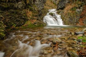 een waterval in een rivier met rotsen bij Apartmaji nad potokom in Železniki