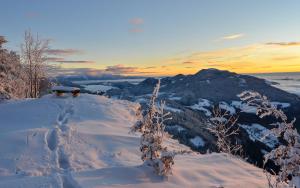 een met sneeuw bedekte berg met de zonsondergang op de achtergrond bij Apartmaji nad potokom in Železniki
