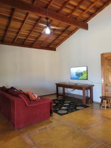 een woonkamer met een rode bank en een tafel bij Chácara Recanto Colibri in Socorro +20 foto's