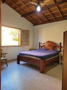 een slaapkamer met een houten bed in een kamer bij Chácara Recanto Colibri in Socorro