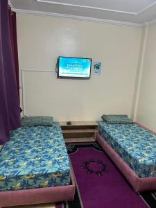 a room with two beds and a tv on the wall at Chez ZAKi in Meknès